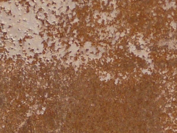 Tan metal texture, almost completely covered by a light, rough surface of dark red rust.